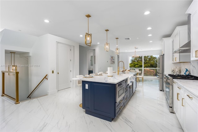 kitchen with blue cabinets, white cabinetry, appliances with stainless steel finishes, pendant lighting, and a kitchen island with sink