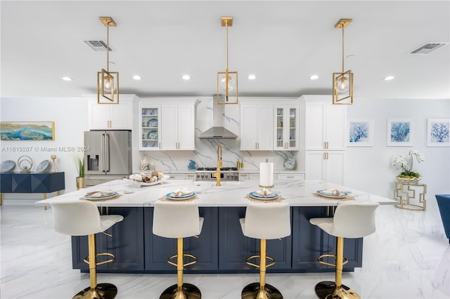 kitchen with pendant lighting, high end fridge, and wall chimney range hood