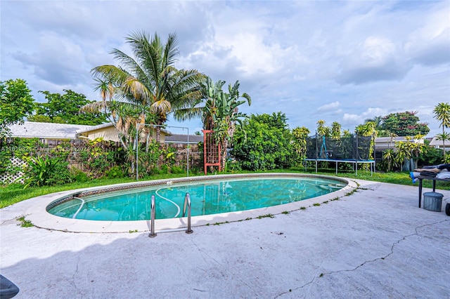 view of swimming pool featuring a trampoline and a patio