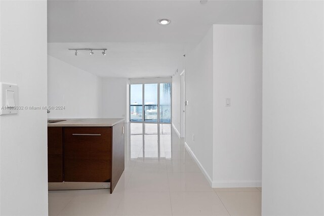 hallway featuring light tile patterned flooring, track lighting, and expansive windows