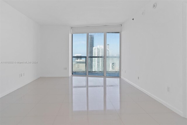 spare room with expansive windows and light tile patterned floors