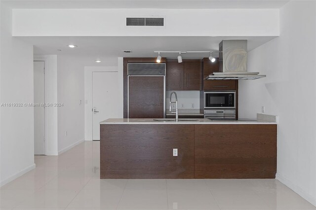 kitchen with built in appliances, sink, light tile patterned flooring, and custom exhaust hood