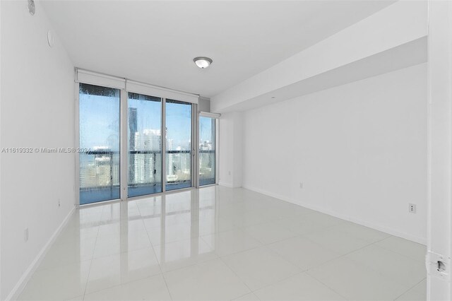 tiled spare room featuring a wall of windows and a healthy amount of sunlight