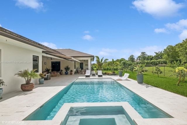 view of pool with a lawn, a patio area, ceiling fan, and an in ground hot tub