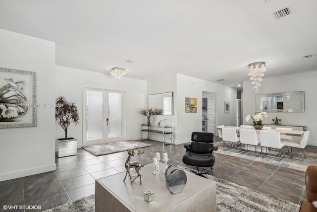 living room with a notable chandelier, dark tile patterned floors, and french doors