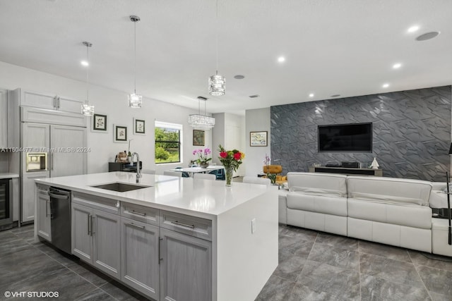 kitchen featuring gray cabinetry, sink, decorative light fixtures, a center island with sink, and dishwasher