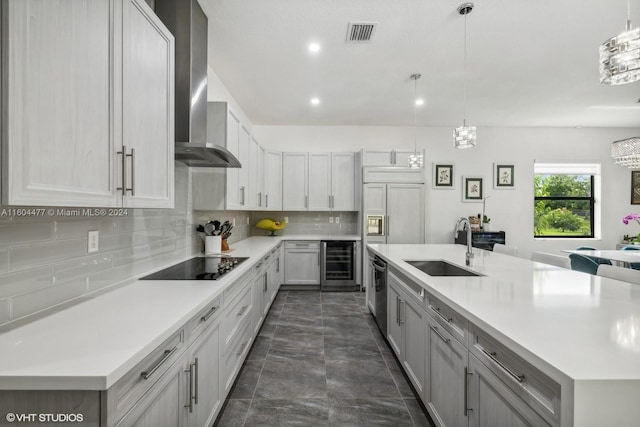 kitchen featuring black electric cooktop, wine cooler, decorative light fixtures, and wall chimney range hood