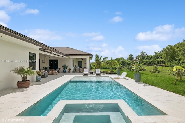 view of pool with a lawn, ceiling fan, a patio area, and an in ground hot tub