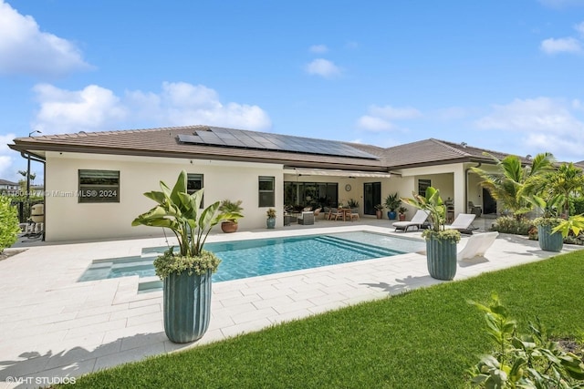 rear view of property with ceiling fan, a patio, and solar panels