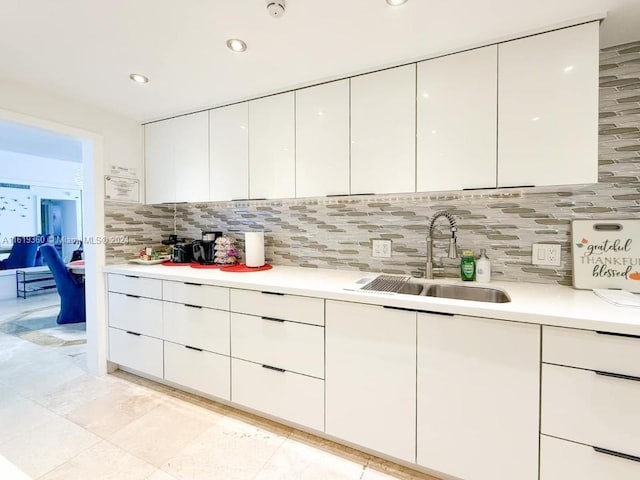 kitchen with tasteful backsplash, sink, and white cabinets