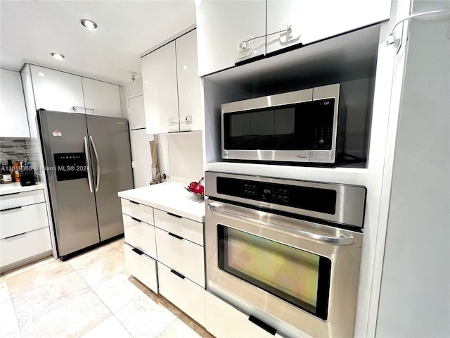 kitchen with decorative backsplash, white cabinetry, and stainless steel appliances