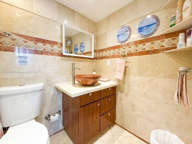 bathroom with vanity, toilet, and tile walls