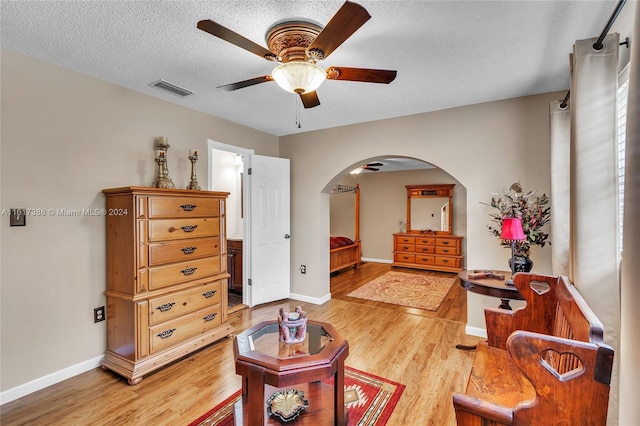 living area featuring hardwood / wood-style floors, ceiling fan, and a textured ceiling