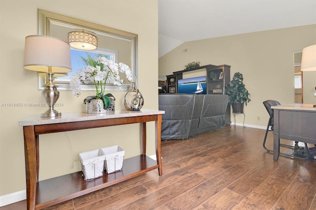 interior space with vaulted ceiling, wood finished floors, and baseboards