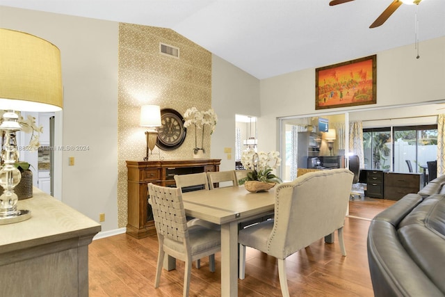 dining area with an accent wall, wood finished floors, visible vents, and wallpapered walls