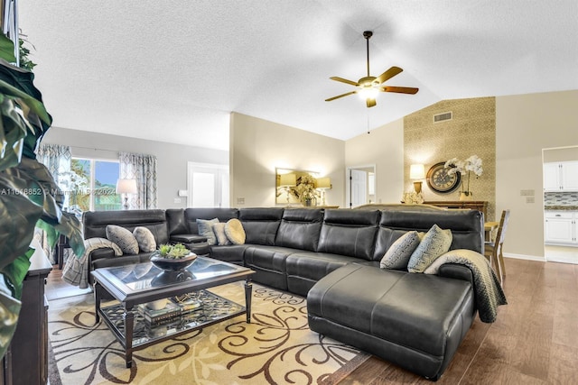 living room with vaulted ceiling, a textured ceiling, ceiling fan, and hardwood / wood-style floors