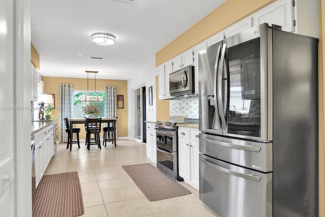 kitchen featuring tasteful backsplash, stainless steel appliances, hanging light fixtures, light tile patterned floors, and white cabinetry