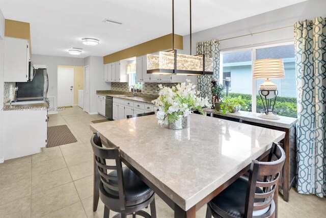 kitchen with white cabinets, a healthy amount of sunlight, dishwashing machine, and tasteful backsplash