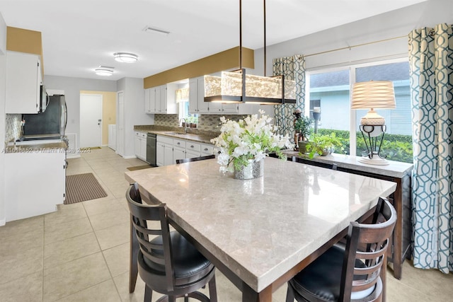 kitchen with black dishwasher, light tile patterned floors, backsplash, and white cabinets