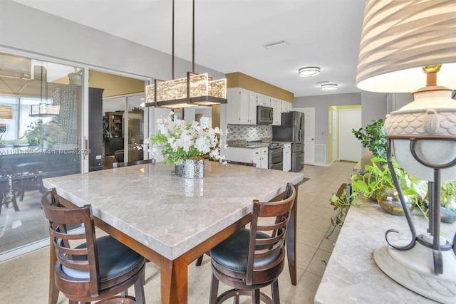 dining space with light tile patterned floors and visible vents