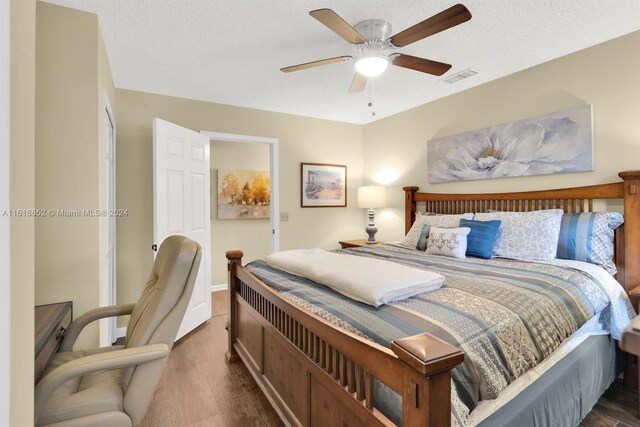 bedroom with ceiling fan, a textured ceiling, and dark hardwood / wood-style flooring