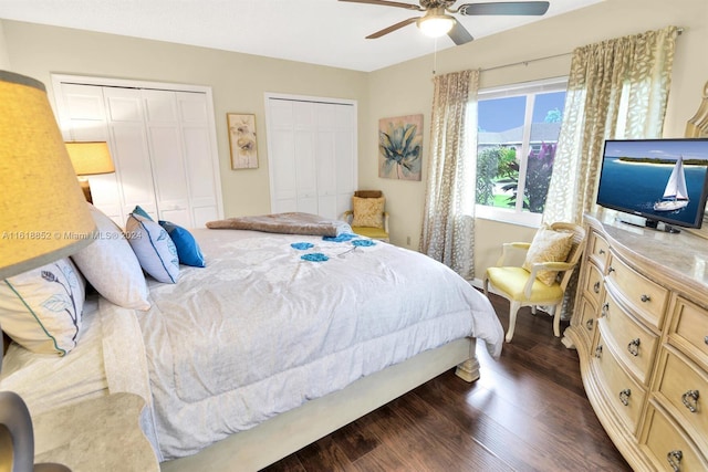 bedroom featuring dark wood-style flooring, two closets, and a ceiling fan