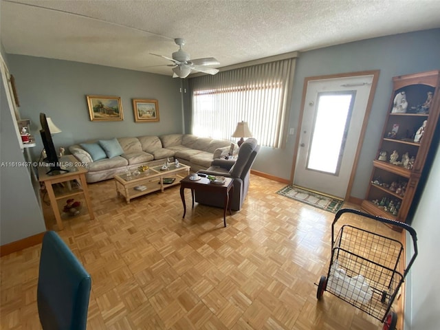 living room with ceiling fan, light parquet floors, and a textured ceiling