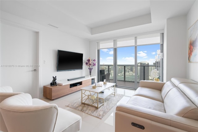 living room with light tile patterned flooring, floor to ceiling windows, and a tray ceiling