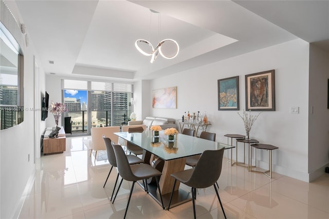 dining room featuring light tile patterned flooring, an inviting chandelier, and a tray ceiling