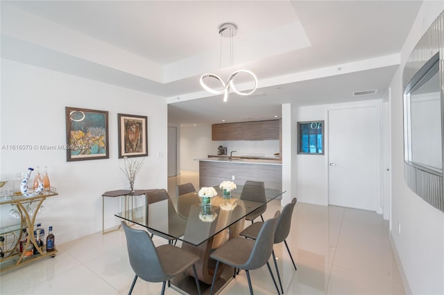 tiled dining space with a chandelier and a tray ceiling