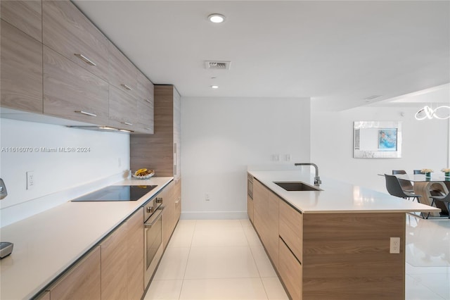 kitchen featuring black electric stovetop, sink, light tile patterned flooring, and oven