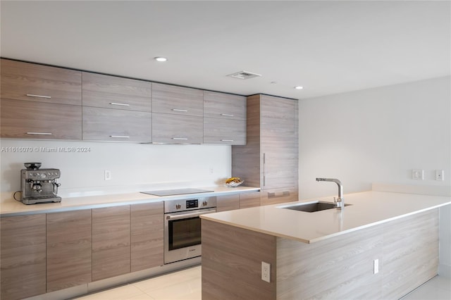 kitchen with black electric stovetop, sink, light tile patterned flooring, and oven