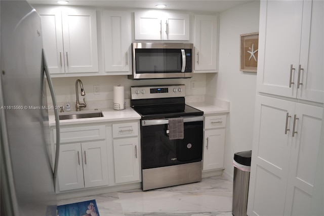 kitchen featuring white cabinets, light tile patterned floors, appliances with stainless steel finishes, and sink