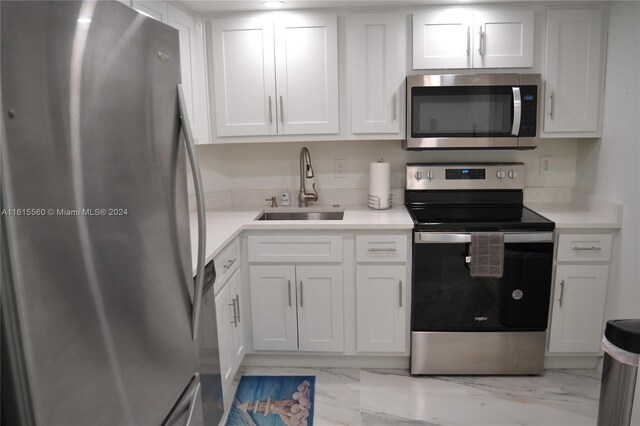 kitchen featuring white cabinetry, stainless steel appliances, light tile patterned flooring, and sink