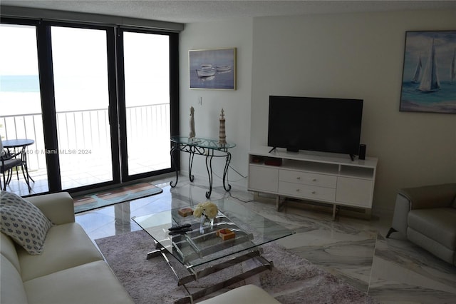 living room with a water view, floor to ceiling windows, and a textured ceiling