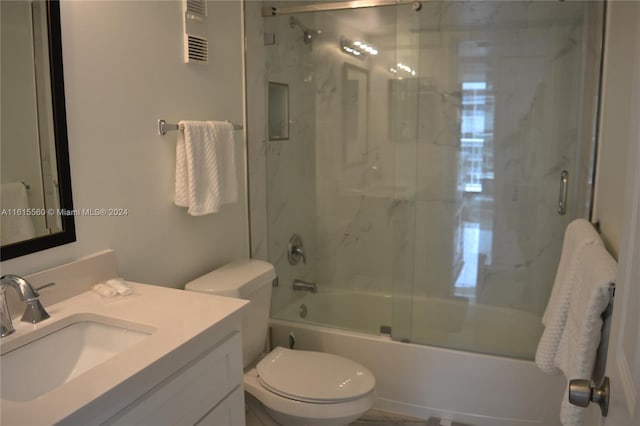 full bathroom with vanity, bath / shower combo with glass door, and toilet