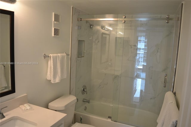 full bathroom featuring enclosed tub / shower combo, vanity, and toilet