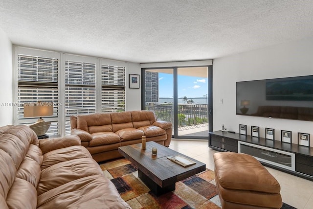 living room with expansive windows, light tile patterned floors, and a textured ceiling