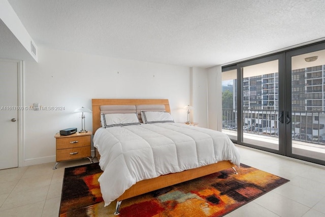 tiled bedroom featuring a textured ceiling, access to exterior, and floor to ceiling windows