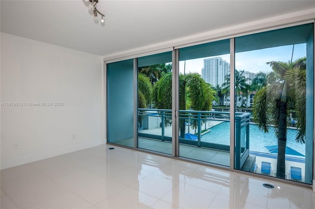 unfurnished room with tile patterned flooring and a wall of windows