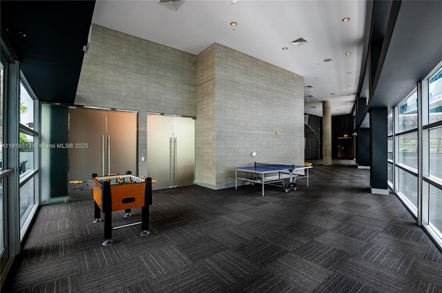 playroom featuring a high ceiling and dark colored carpet