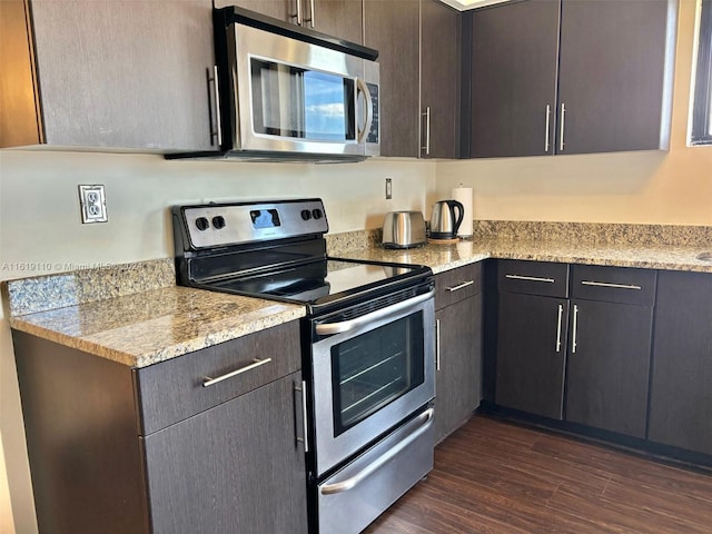 kitchen with appliances with stainless steel finishes, dark brown cabinets, dark hardwood / wood-style flooring, and light stone countertops