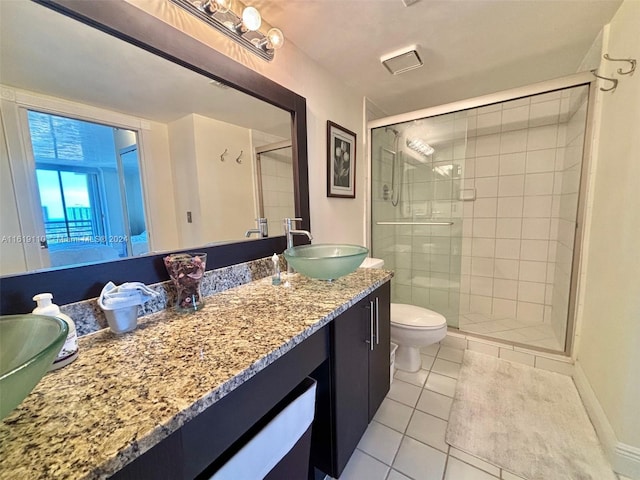 bathroom featuring toilet, vanity, tile patterned flooring, and a shower with door