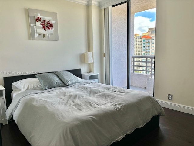 bedroom featuring dark wood-type flooring, ornamental molding, and access to outside