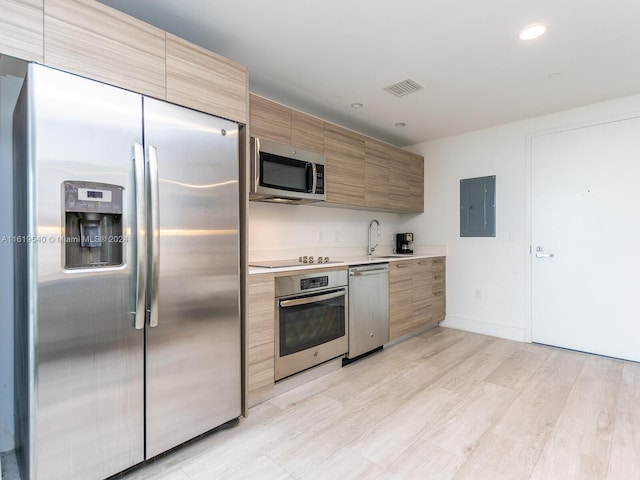 kitchen featuring sink, stainless steel appliances, light hardwood / wood-style floors, and electric panel