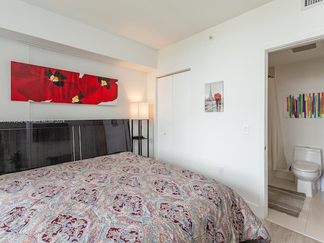 bedroom with a closet, ensuite bathroom, and tile patterned flooring