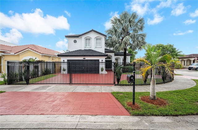 mediterranean / spanish-style house with a tile roof, a fenced front yard, a gate, decorative driveway, and stucco siding