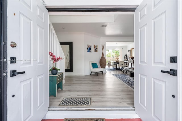 entrance foyer with baseboards, visible vents, stairway, wood finished floors, and crown molding