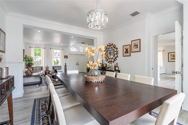 living room featuring light wood-type flooring, a chandelier, and ornamental molding