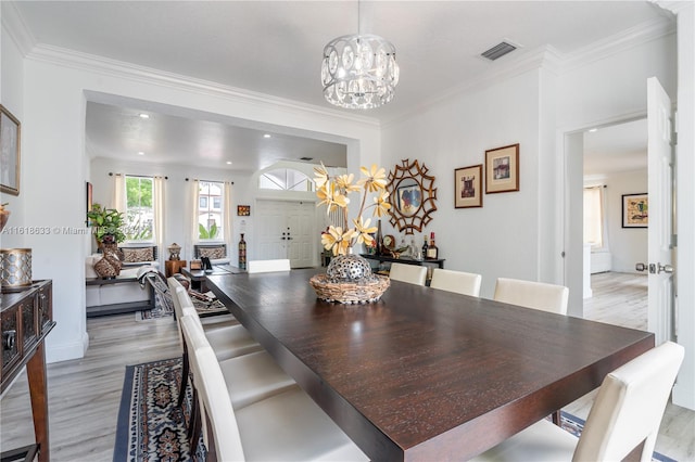 dining area featuring a notable chandelier, crown molding, and light hardwood / wood-style floors